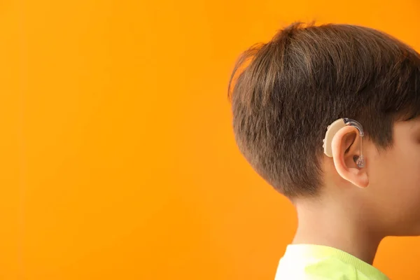 Niño pequeño con audífono sobre fondo de color — Foto de Stock