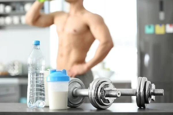 Protein shake, bottle of water and dumbbells on table — Stock Photo, Image