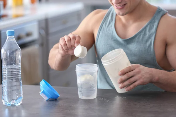 Sporty man making protein shake at home