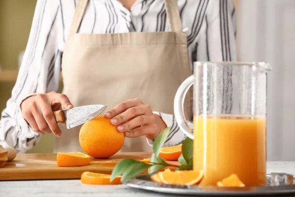 Femme préparant savoureux jus d'orange à table dans la cuisine — Photo