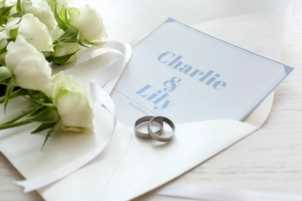 Zaproszenia ślubne, obrączki i kwiaty na stole — Zdjęcie stockowe