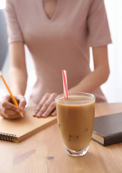 Glass of tasty frappe coffee on table of young woman — Stock Photo, Image