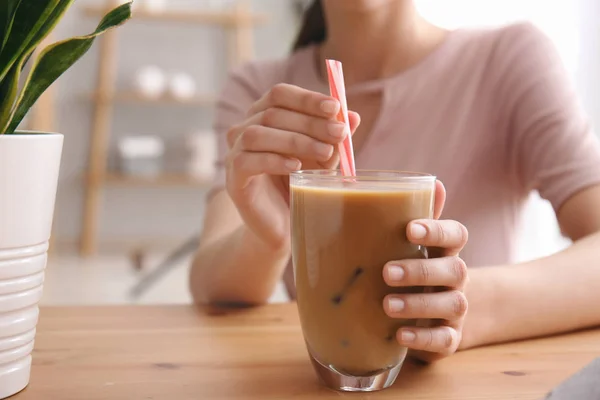 Vrouw drinken smakelijke frappe koffie aan tafel — Stockfoto