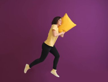 Renk arka plan karşı yastık ile genç kadın atlama