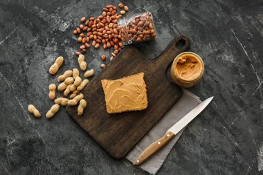 Gri arka planda lezzetli fıstık ezmesi ve ekmek ile ahşap tahta