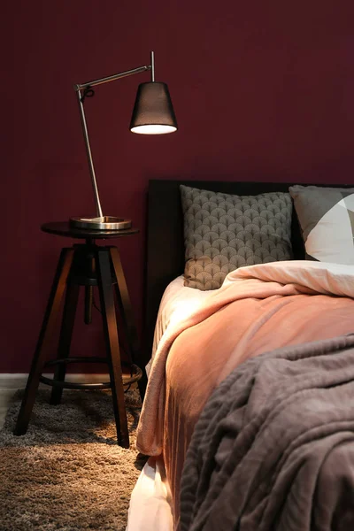 Big comfortable bed with lamp on table in room — Stock Photo, Image