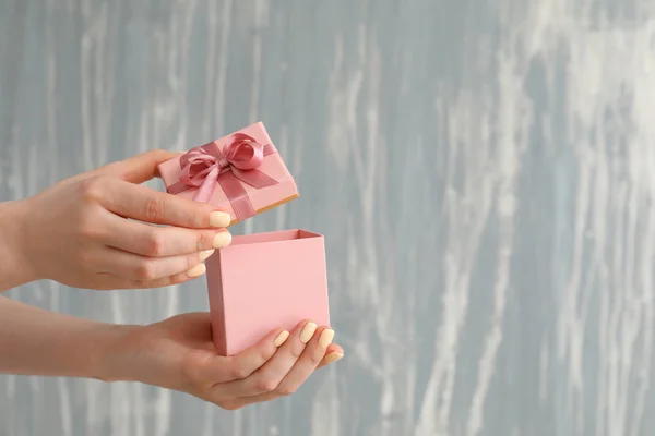 Female hands with gift box on grey background — Stock Photo, Image