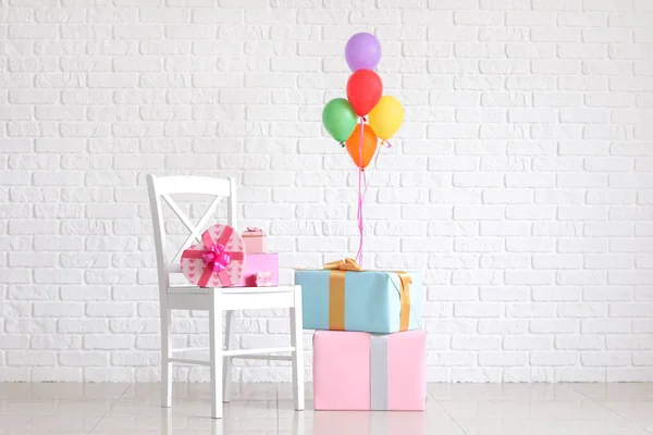 Beautiful gifts with air balloons near white brick wall — Stock Photo, Image