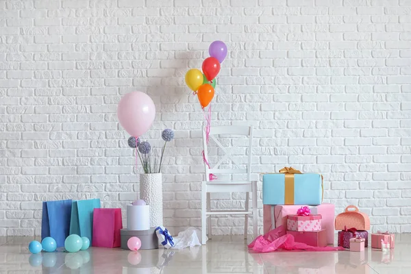 Vackra presenter med luft ballonger på golvet nära vit tegel vägg — Stockfoto