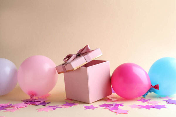 Красивая подарочная коробка с праздничным декором на цветном фоне
