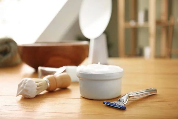 Tigela com espuma de barbear, navalha e escova na mesa no banheiro — Fotografia de Stock