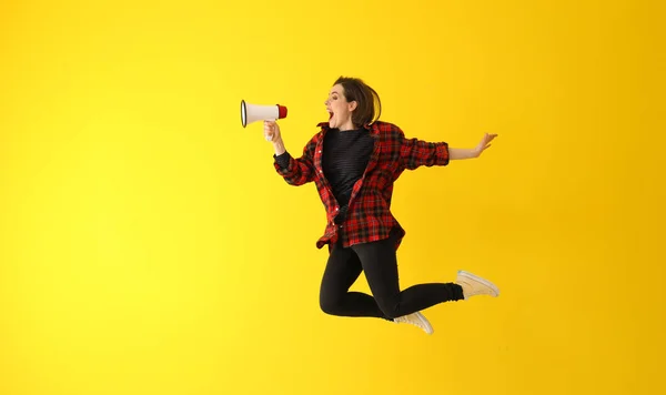 Hoppande ung kvinna med MegaFon mot färg bakgrund — Stockfoto