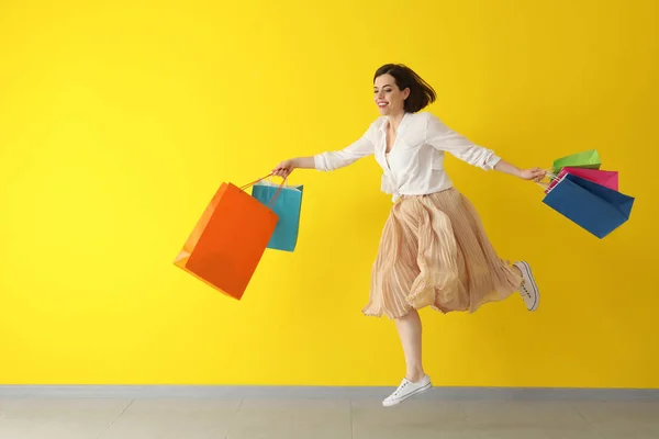 Running jonge vrouw met boodschappentassen tegen kleur achtergrond — Stockfoto