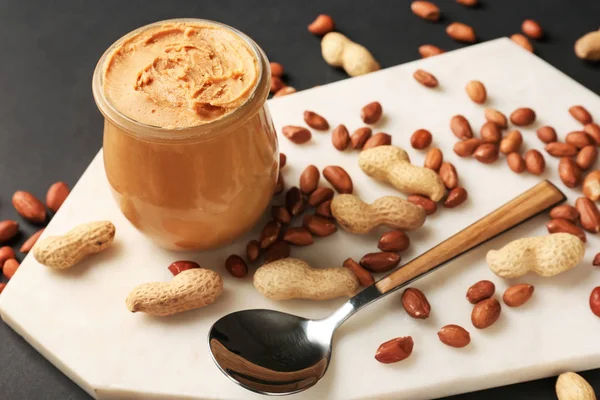 Jar with tasty peanut butter on board — Stock Photo, Image