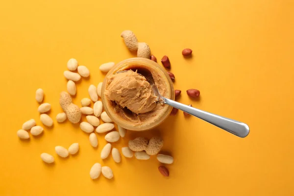 Jar with tasty peanut butter on color background — Stock Photo, Image