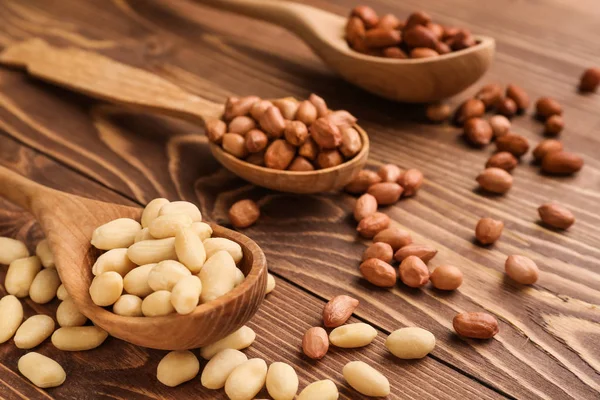 Ложки зі смачними арахісами на дерев'яному фоні — стокове фото