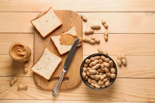 Placa com manteiga de amendoim saborosa e pão no fundo de madeira — Fotografia de Stock