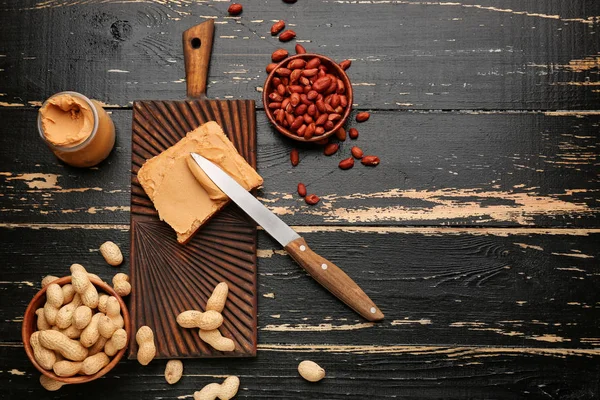 Placa com manteiga de amendoim saborosa e pão no fundo de madeira — Fotografia de Stock