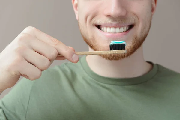 Mladý muž čištění zubů na pozadí barev, zaostřená — Stock fotografie