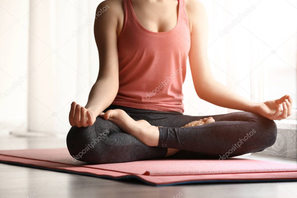 Sporty young woman practicing yoga indoors