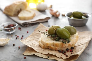 Gri masada ekmek ve baharatlar ile lezzetli zeytin