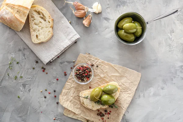 Olives savoureuses avec pain et épices sur table grise — Photo