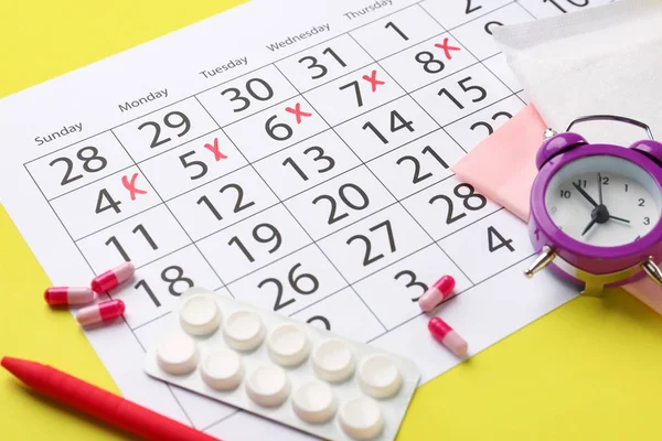 Calendario menstrual con píldoras y despertador sobre fondo de color — Foto de Stock