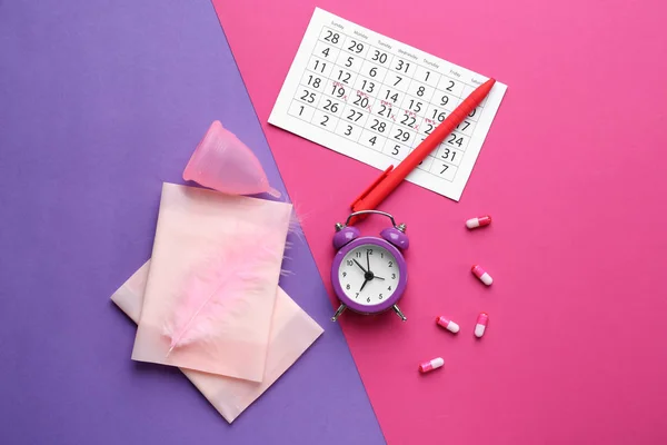 色の背景にフェミニンな製品、丸薬と目覚まし時計と月経カレンダー — ストック写真