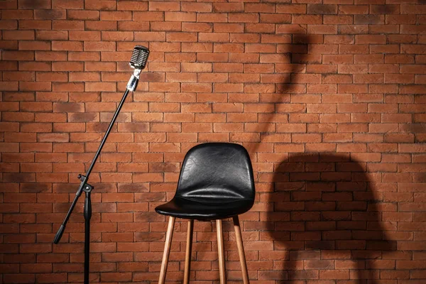 Microfoon met stoel op baksteen achtergrond — Stockfoto