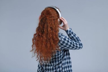 Kulaklık ile genç kadın gri arka planda müzik dinlerken