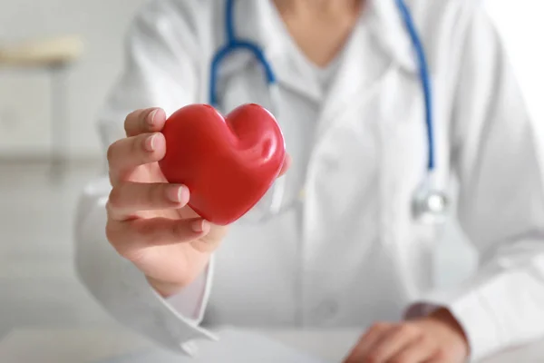 Cardiologista com coração vermelho na clínica, close-up — Fotografia de Stock