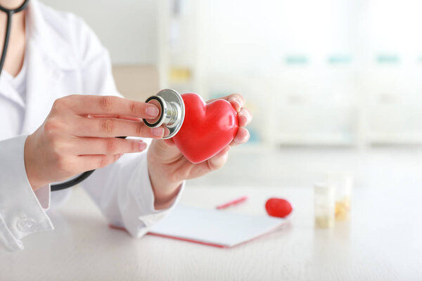 Cardiologist with red heart and stethoscope in clinic
