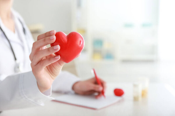 Cardiologist with red heart in clinic, closeup