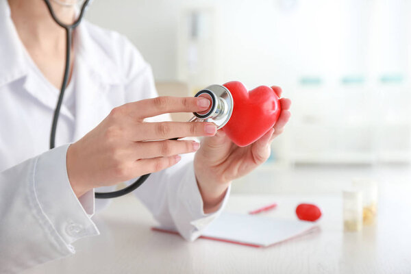Cardiologist with red heart and stethoscope in clinic