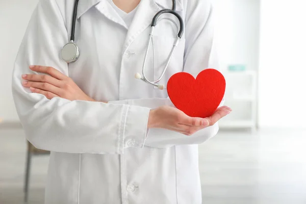 Cardiologista com coração vermelho na clínica — Fotografia de Stock