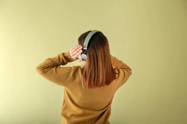 Ung kvinde med hovedtelefoner lytter til musik på farve baggrund - Stock-foto