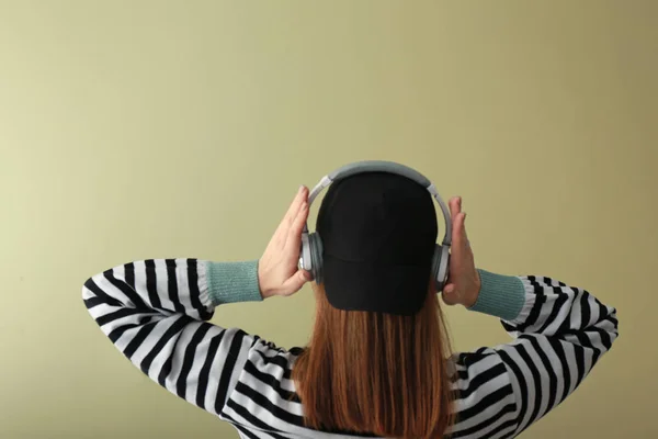 Mujer joven con auriculares escuchando música sobre fondo de color —  Fotos de Stock