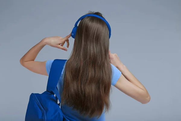 Ung kvinna med hörlurar lyssnar på musik på grå bakgrund — Stockfoto