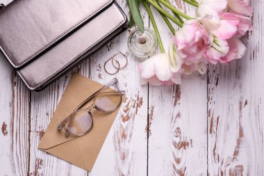 Beyaz ahşap arka planda zarf ve kadın aksesuarları ile güzel lale