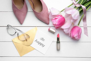 Beyaz ahşap arka planda tebrik kartı ve kadın aksesuarları ile güzel lale