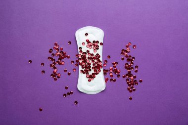Renk arka planda kırmızı payetler ile menstrüel Pad. Menstrasyon konsepti