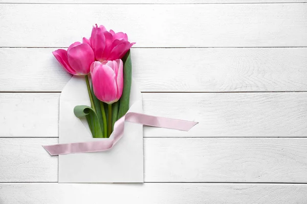 Beautiful tulips with envelope on white wooden background — Stock Photo, Image