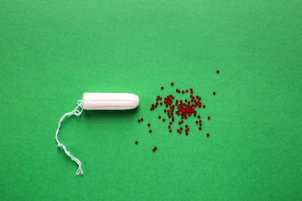 Tampon und rote Perlen auf farbigem Hintergrund. Menstruationskonzept — Stockfoto