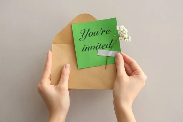 Female hands with invitation and envelope on grey background — Stock Photo, Image