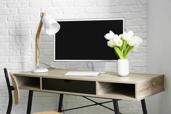 Vase with beautiful tulips on table with computer — Stock Photo, Image