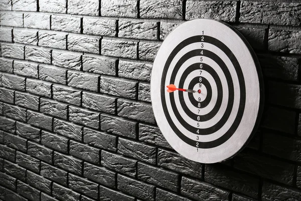 Koyu tuğla duvar üzerinde hit Bullseye ile dartboard