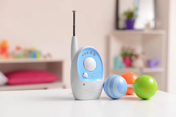 Modern baby monitor with rattle on table in room — Stock Photo, Image