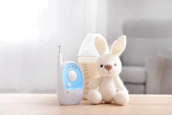 Modern baby monitor with toy and bottle of milk on table in room — Stock Photo, Image