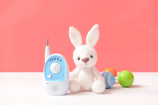 Modern baby monitor with toys on table against color background — Stock Photo, Image