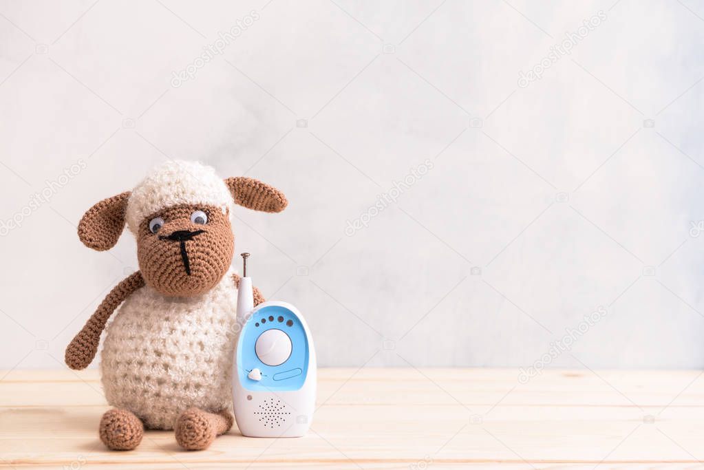 Modern baby monitor with toy on wooden table
